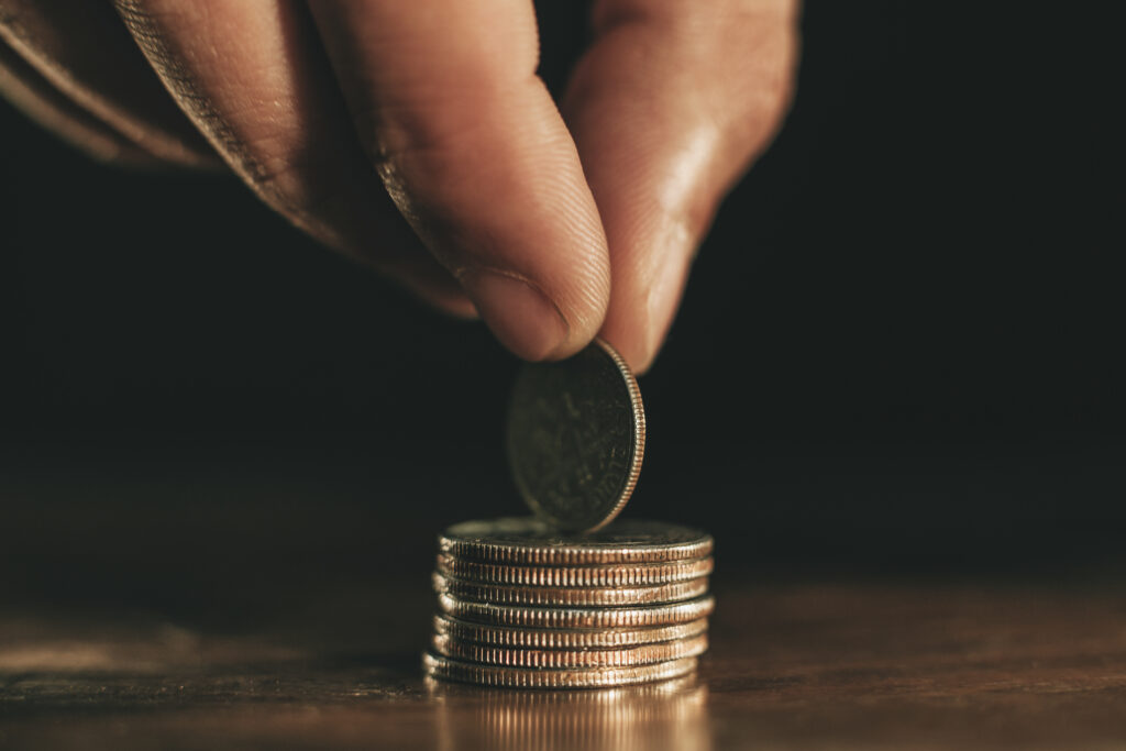 Hand holding coin on top of stack of coins