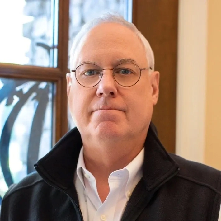 A man with glasses and a black jacket