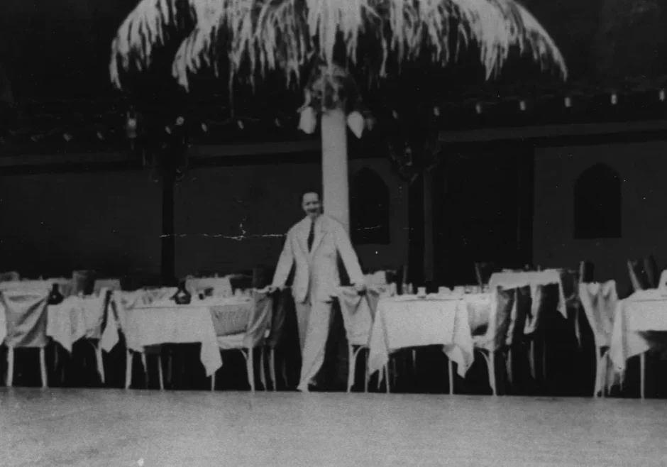 A man standing in front of a table with many chairs.